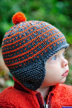 a young boy wearing a knitted hat with an orange pom - pom