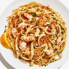 pasta with shrimp and parmesan cheese in a white bowl next to an orange slice