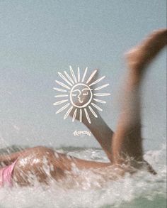 a woman swimming in the ocean with her hand up to her face and sun above her head