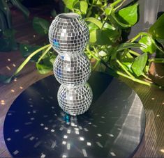 three mirrored disco balls sitting on top of a black table next to a planter