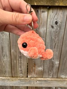 a hand holding a keychain with an orange and white stuffed animal hanging from it's side