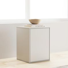 a white cabinet sitting in front of a window with a bowl on top of it