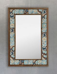 a mirror hanging on the wall with blue and brown tiles around it's edges