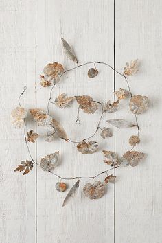 an arrangement of dried leaves on a white wood background with the word love written in it