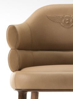 a tan leather chair with an emblem on the back and arm rests against a white background