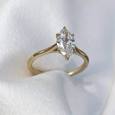 a close up view of a diamond ring on a white cloth with the fabric in the background