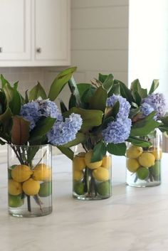 three vases with lemons and blue flowers in them on a kitchen countertop