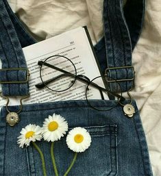 some daisies are sitting in the pocket of a pair of blue jean overalls