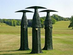 three tall metal sculptures sitting in the middle of a field