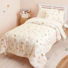 a small child's bed with a white comforter and teddy bear on it