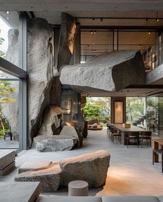 the interior of a modern house with large rocks and tables in front of it,