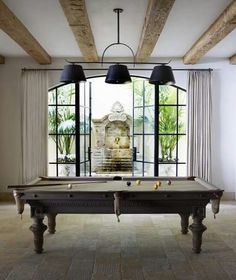 a pool table in the middle of a room with two lamps hanging from it's ceiling