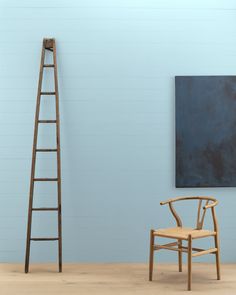 a ladder leaning up against a wall next to a chair and painting on the wall