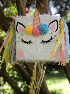 a unicorn pinata hanging from a tree with flowers on it's head and eyes