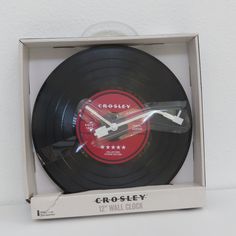 a black and red clock in a box on a white surface with the word crosley printed on it