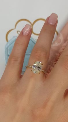 a woman's hand with a diamond ring on top of her finger and an oval shaped diamond in the middle