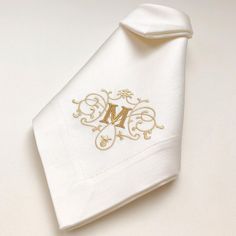 an embroidered monogram on the side of a white shirt with gold trimmings