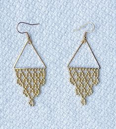 two pairs of gold earrings on top of a white cloth covered surface, one with an openwork design and the other with beads