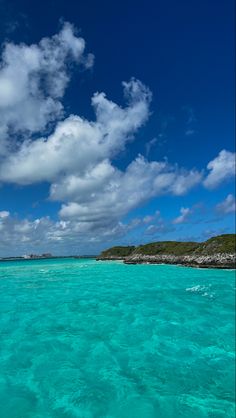 the water is very clear and blue with some clouds in the sky above it on a sunny day