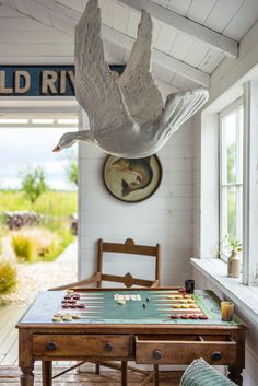 a game table in the middle of a room with a bird sculpture hanging over it