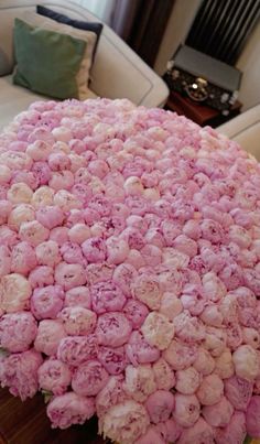 a large pile of pink flowers sitting on top of a table next to a couch