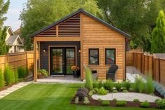 a small wooden house sitting on top of a lush green field next to a fence