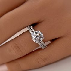 a woman's hand with a diamond ring on top of her finger and an engagement band