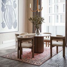 a dining room table with chairs and a chandelier hanging from the ceiling in front of a large window