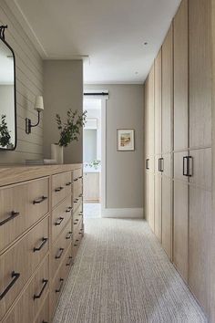 an empty hallway leading to a bedroom with large wooden cabinets and drawers on both sides