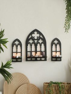 three candles are lit on the wall in front of two arched - windowed windows