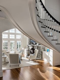 there is a staircase in the middle of this living room with white furniture and wood floors