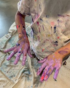 two hands covered in paint sitting on top of a table