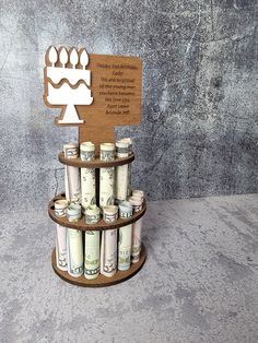 a cake with candles and money in it on a wooden display stand against a concrete wall