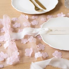 a table topped with plates and napkins covered in pink confetti streamers