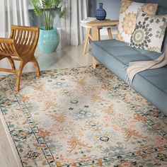 a living room area with a blue couch, chair and large rug on the floor