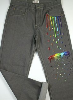 a pair of grey jeans with rainbow paint splattered on the front and back