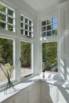 the sun shines through three windows in a white room with vases and flowers