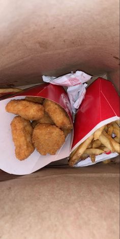 chicken nuggets and french fries in a red paper bag