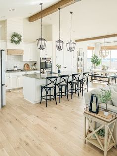 a large open kitchen and living room with white walls, wood flooring and wooden beams