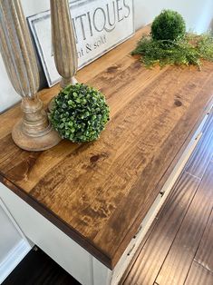 a wooden table topped with a potted plant next to a lamp on top of it