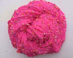 a pink ball of yarn with sprinkles on it sitting on a white surface