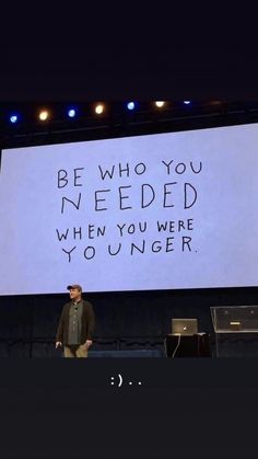 a man standing in front of a large screen with writing on it that says be who you needed when you were younger