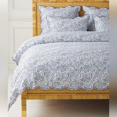 a bed with blue and white bedspread, pillows and pillow cases on it