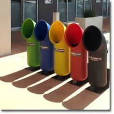 several different colored trash cans lined up in front of a building