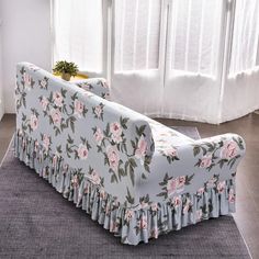 a couch that is sitting on the floor in front of a window with white curtains