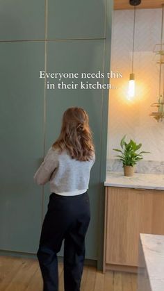 a woman standing in front of a green wall with the words everyone needs this in their kitchen