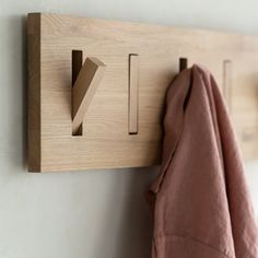 a wooden coat rack with hooks and clothes hanging from it's sides on a wall