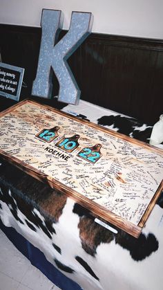 a large wooden table sitting on top of a cow skin covered floor next to a letter k