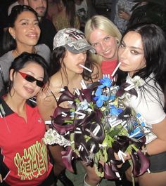 a group of young women standing next to each other at a party with drinks in their mouths