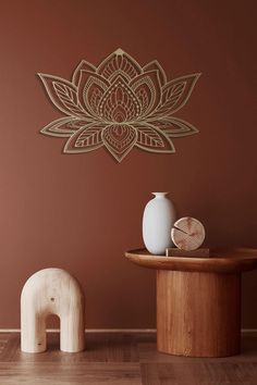 an elephant statue sitting next to a vase on top of a wooden table in front of a brown wall